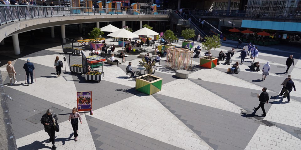 Många människor som rör sig över ett stort rutmönstrat torg.
