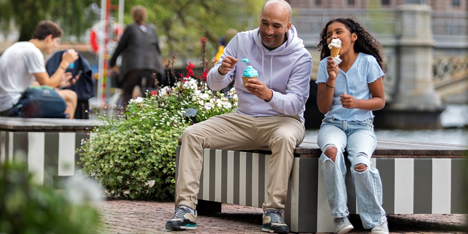 En man och en flicka som äter glas på en bänk