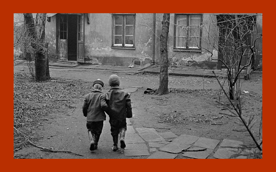 Två barn fotade bakifrån på en gård 1950-tal. Foto.