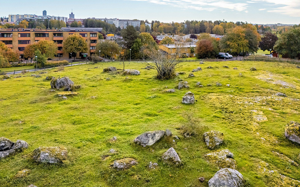 Kulle med stenar utspritt. Nedanför kullen finns bostadshus.