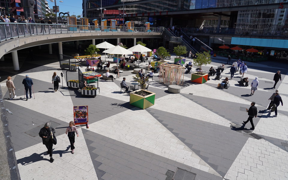 Många människor som rör sig över ett stort rutmönstrat torg.